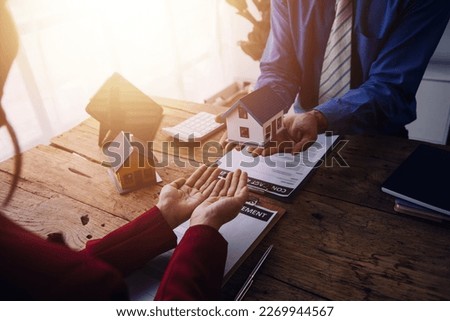 Real estate broker agent presenting and consult to customer to decision making sign insurance form agreement, buy and sell home model, concerning mortgage loan offer for and house insurance