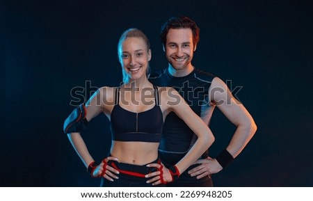 Happy smiling fit couple at the gym isolated on black background. Fitness concept. Healthy life style. Sports wallpaper for sports advertising. Picture for a sports article in a magazine, website.