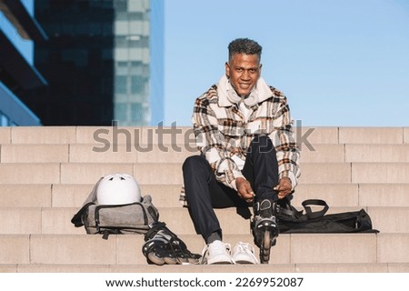 Man preparing to roller skate, putting on skates. Upright image
