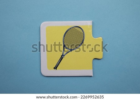 Colorful educational puzzle pieces with pictures of tennis rackets placed on a blue background.