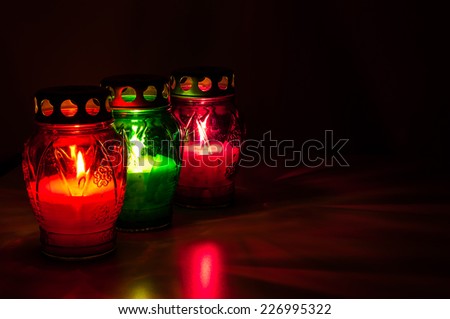 Closeup of colored burning votive candles in the dark