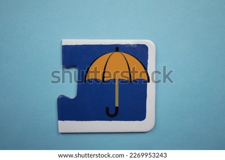 Educational puzzle pieces with colorful umbrella pictures placed on a blue background.