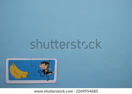 Colorful educational puzzle pieces with pictures of bananas and monkeys placed on the lower left of the blue background.