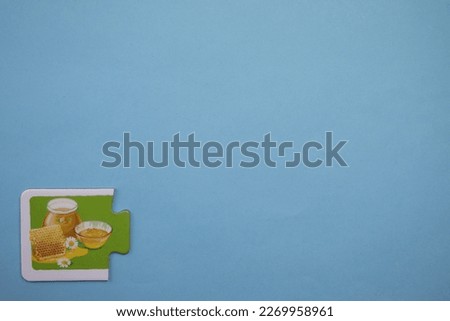 Colorful honey-picture educational puzzle pieces placed on the lower left of the blue background.