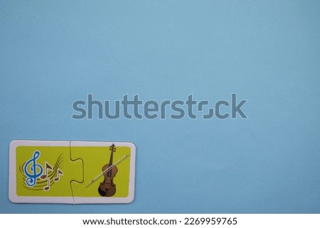 Colorful educational puzzle pieces with musical notes and violins placed on the lower left of the blue background.