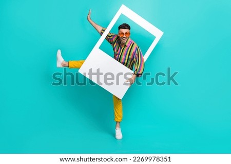 Full length photo of positive man dressed striped shirt yellow pants dancing in photo frame isolated on turquoise color background