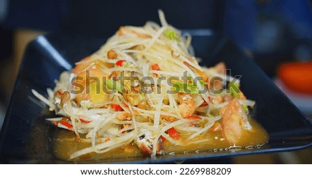 Close up person holding dish of cooked healthy yummy fresh vegetables spicy Green papaya salad or Som Tum, Thai street food Thai cuisine