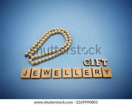 selective focus on the arrangement of the brown alphabet and the black alphabet in a brown box on a blue vignette background. There is also a white jewelery chain