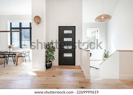 Contemporary home with minimal furnishings and decor light wood floor stairs white walls large windows with black frames and simple style Royalty-Free Stock Photo #2269999619