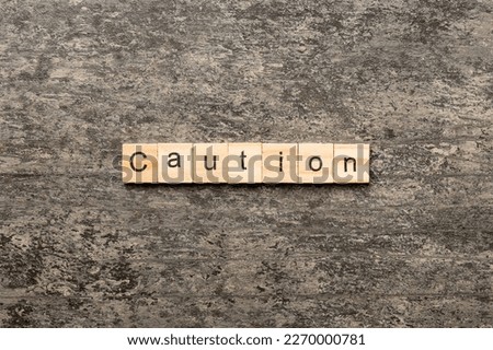 CAUTION word written on wood block. CAUTION text on cement table for your desing, concept.