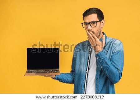 Shocked amazed surprized businessman pointing finger on blank laptop screen isolated over yellow background. Looking at camera.