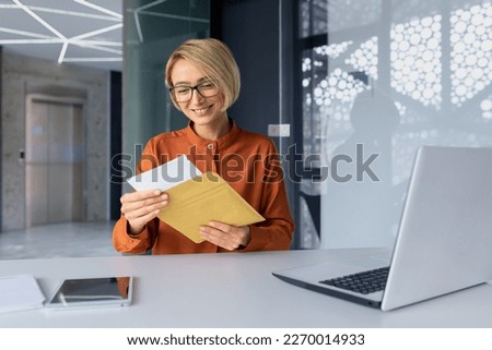 Successful business woman boss working inside office with laptop, employee received mail envelope letter with notification message, blonde woman reading and smiling good news, happy with achievement. Royalty-Free Stock Photo #2270014933