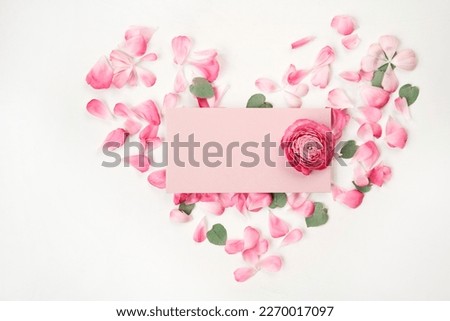 Love letter. white card with pink paper envelope mock up. Petals of flowers, roses and ranunculus. Valentine's day romantic background . Space for text.