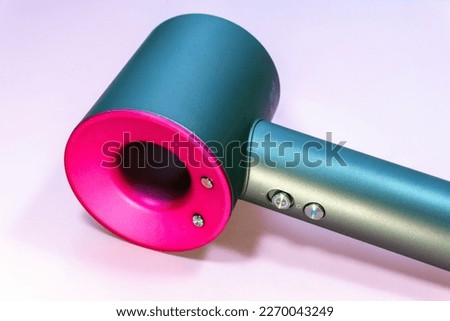 Careful hair care. Close-up of a modern hair dryer on a pink background. Beauty and fashion concept. Macro, selective focus, horizontal photo.  Royalty-Free Stock Photo #2270043249