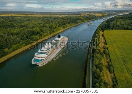 Cruise ship passing Kiel canal . Cruise ship sailing out from Kieler Förde to North Sea, Schleswig-Holstein, Germany. Ships traffic on the Kiel Canal. 
 Royalty-Free Stock Photo #2270057531