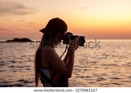 Silhouette of woman with camera. Photographer on the ocean beach during sunset