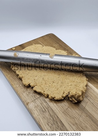 Pictures of ground nuts cookie dough being flatten by a roller.