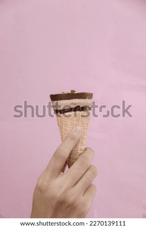 Ice cream is held by a woman on a pink background