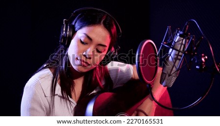 Asian woman performing guitar acoustic solo intro in the recording songs in studio