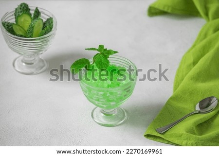 Summer Sicilian dessert granita, frozen juice of fresh cucumber and mint on a white background. Summer cooling, tonic cocktail of crushed ice, a kind of sherbet.