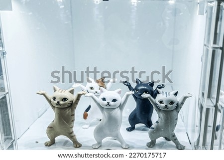 a landscape picture of cat toys with funny pose in a transparent glass box and white background
