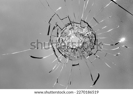 Impact point of bullet in cracked and fragmented glass surface Royalty-Free Stock Photo #2270186519