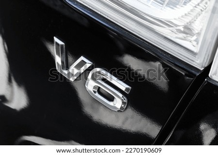 Shiny chrome V6 mark on black back car hood. High performance six-cylinder engine sign