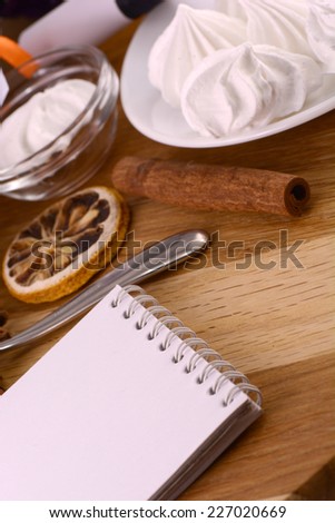 meringue, lemon and cinnamon with empty paper note on wooden background
