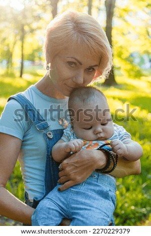 beautiful girl holding a child in her arms in a summer park close-up