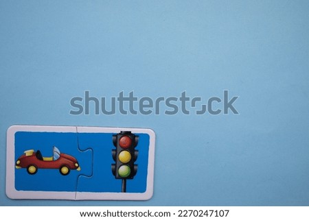 Colorful educational puzzle with pictures of cars and traffic lights placed on the lower left side of a blue background.