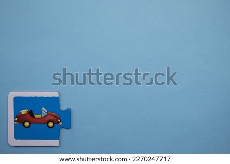 Educational puzzle with colorful pictures of cars placed on the lower left side of a blue background.
