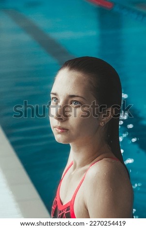 Young beautiful brunette girl on the background of the pool. Portrait of a girl near the side of the pool. Swimming, healthy lifestyle