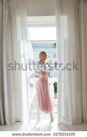 a woman in a pink skirt stands at the door of the balcony in the room