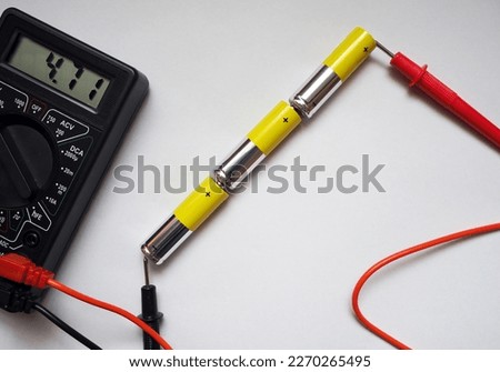 Serial connected three alkaline batteries. Voltage testing cell batteries with voltmeter.            Royalty-Free Stock Photo #2270265495