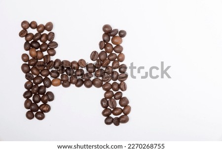 H is a capital letter of the English alphabet made up of natural roasted coffee beans that lie on a white background. Plenty of space to put text or pictures, top view and studio photography.