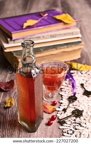 Wine pink color in a small vintage bottle on the background of old books