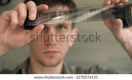 A young photo lab technician looks at an old archival film. close-up