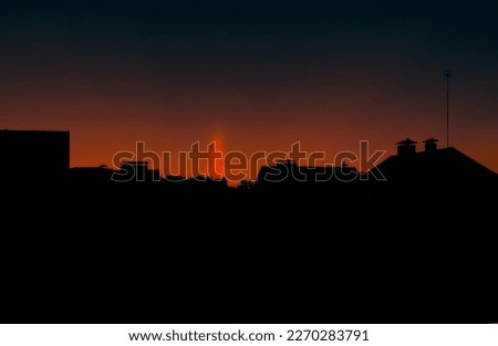 A natural phenomenon of a Light Column. Visual Atmospheric Phenomenon, Optical effect, Sunlight refracting in the air at sunset beautiful sunset sky over the roofs of houses.Banner,Poster.Dramatic sky