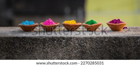 happy holi. gullal or abir, which are colorful powders for holi kept on clay pots or lamps on occasion of indian festival of colors. holi or dolyatra is festival of colors in india. Royalty-Free Stock Photo #2270285031