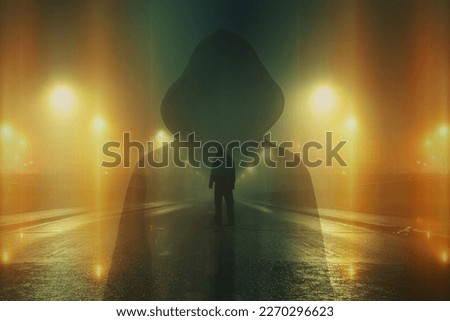 A double exposure of a mysterious hooded figure. Looking down an empty city street. On a spooky foggy winters night. With blurred abstract glowing lights. Royalty-Free Stock Photo #2270296623