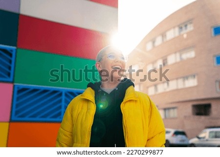 portrait lgbt girl short hair blonde laughing happy with colored building and sunlight