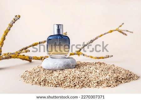 Perfume in a spray bottle on a podium made of stone and tree branches with lichens on a beige background Royalty-Free Stock Photo #2270307371