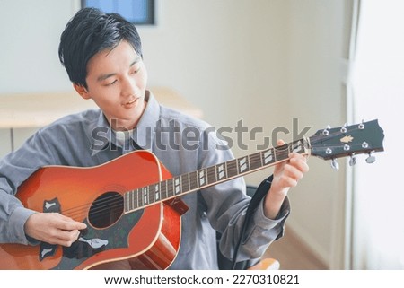 Young man playing acoustic guitar at home Royalty-Free Stock Photo #2270310821
