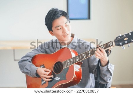 Young man playing acoustic guitar at home Royalty-Free Stock Photo #2270310837