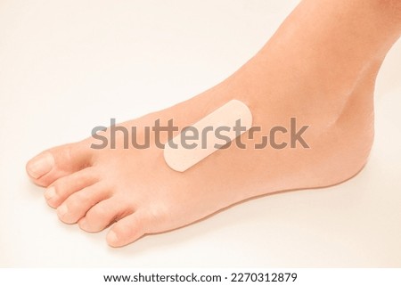 Medical band-aid is glued on top of woman foot, selective focus