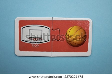 Colorful educational puzzle with basketball hoop and basketball picture placed on a blue background.