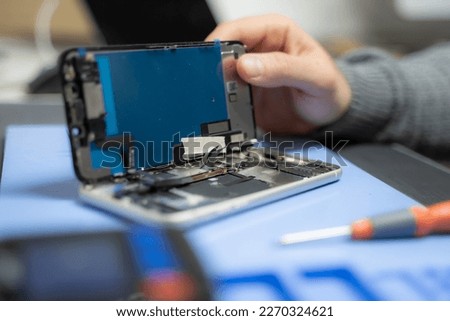 Hands of a man opening a broken mobile in a repair shop