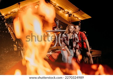 Happy lovely couple relaxing in glamping on evening near cozy bonfire. Luxury camping tent for outdoor recreation and recreation. Lifestyle concept