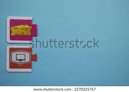 Educational puzzle with basketball hoop and cheese picture placed at lower left of blue background.