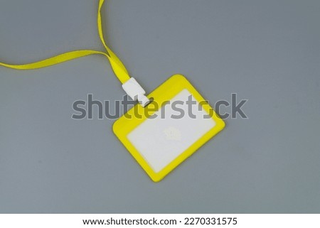 Blank yellow badge with string on gray background close up.